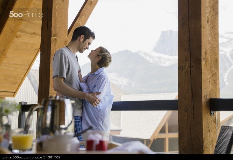 stock-photo-couple-hugging-on-balcony-with-mountain-view-84361769