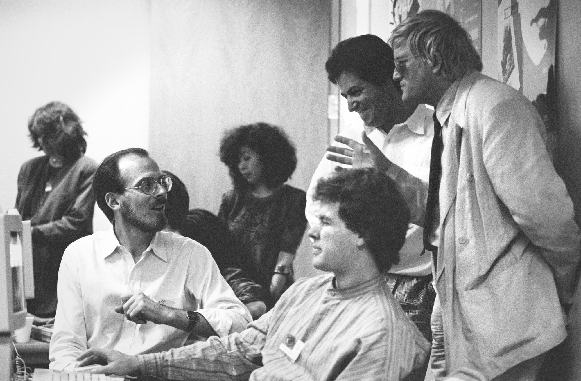 Adobe Creative Director Russell Brown (left, seated) with artists Nicholas Callaway (center, seated) and David Hockney (right, standing) and other colleagues at Adobe's Art Directors Invitational, 1990