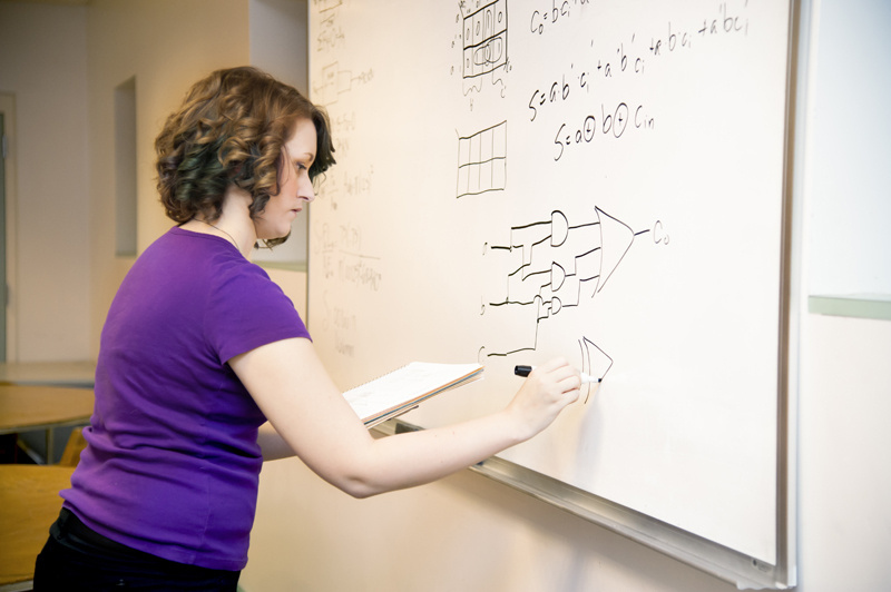 Woman doing equations on dry erase board.