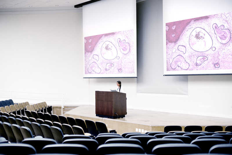 Medical doctor giving presentation to an empty auditorium.