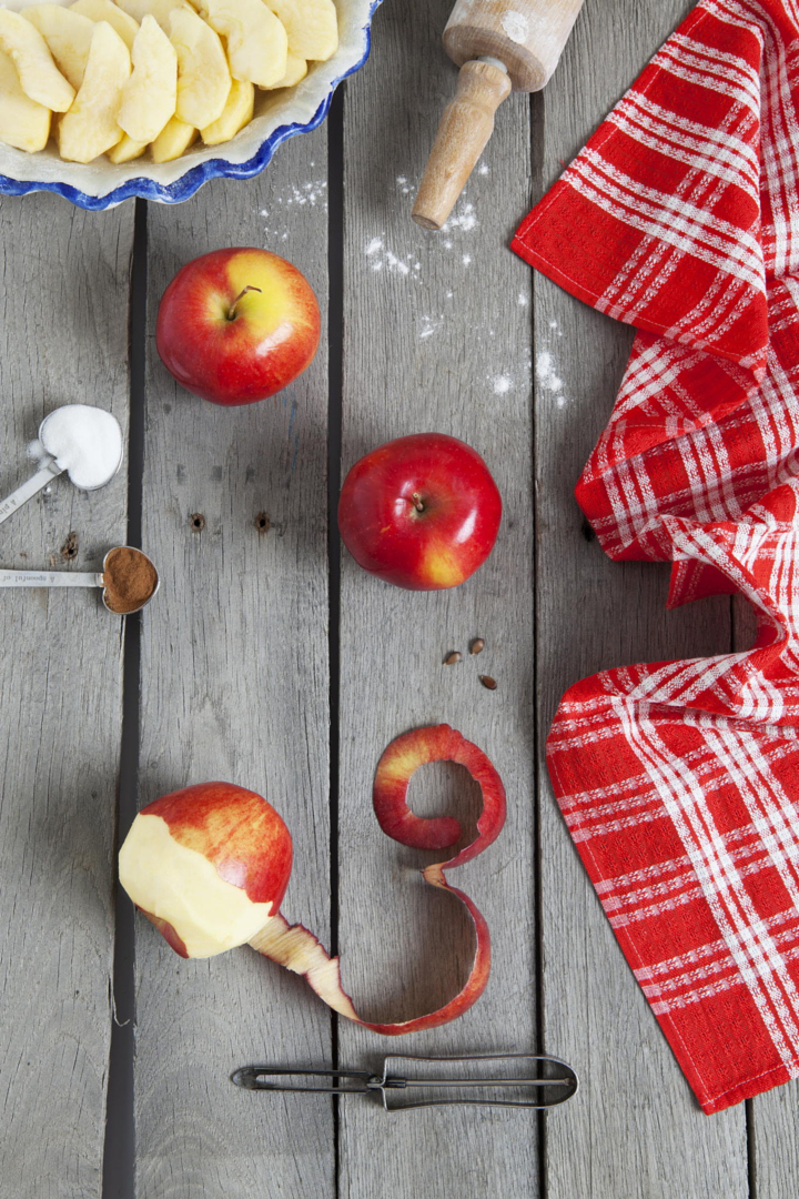 Apple pie ingredients on a raw, weathered wood background.