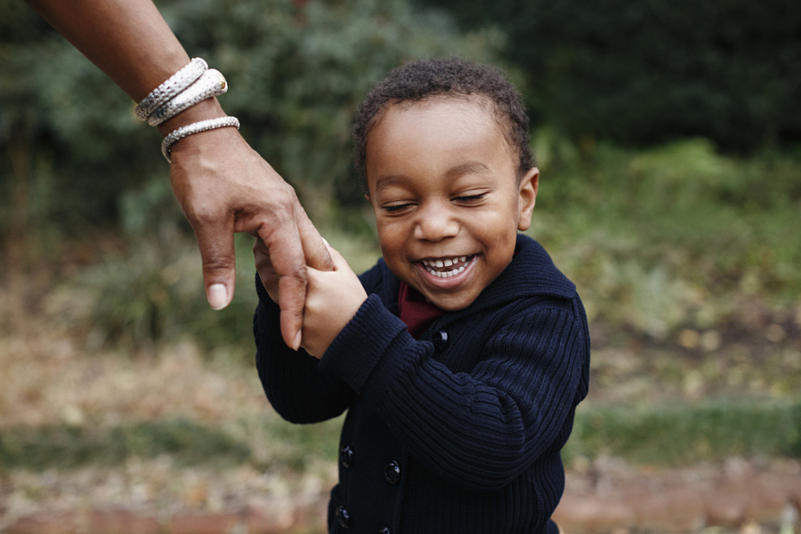 African American boy holding hand of mother in park