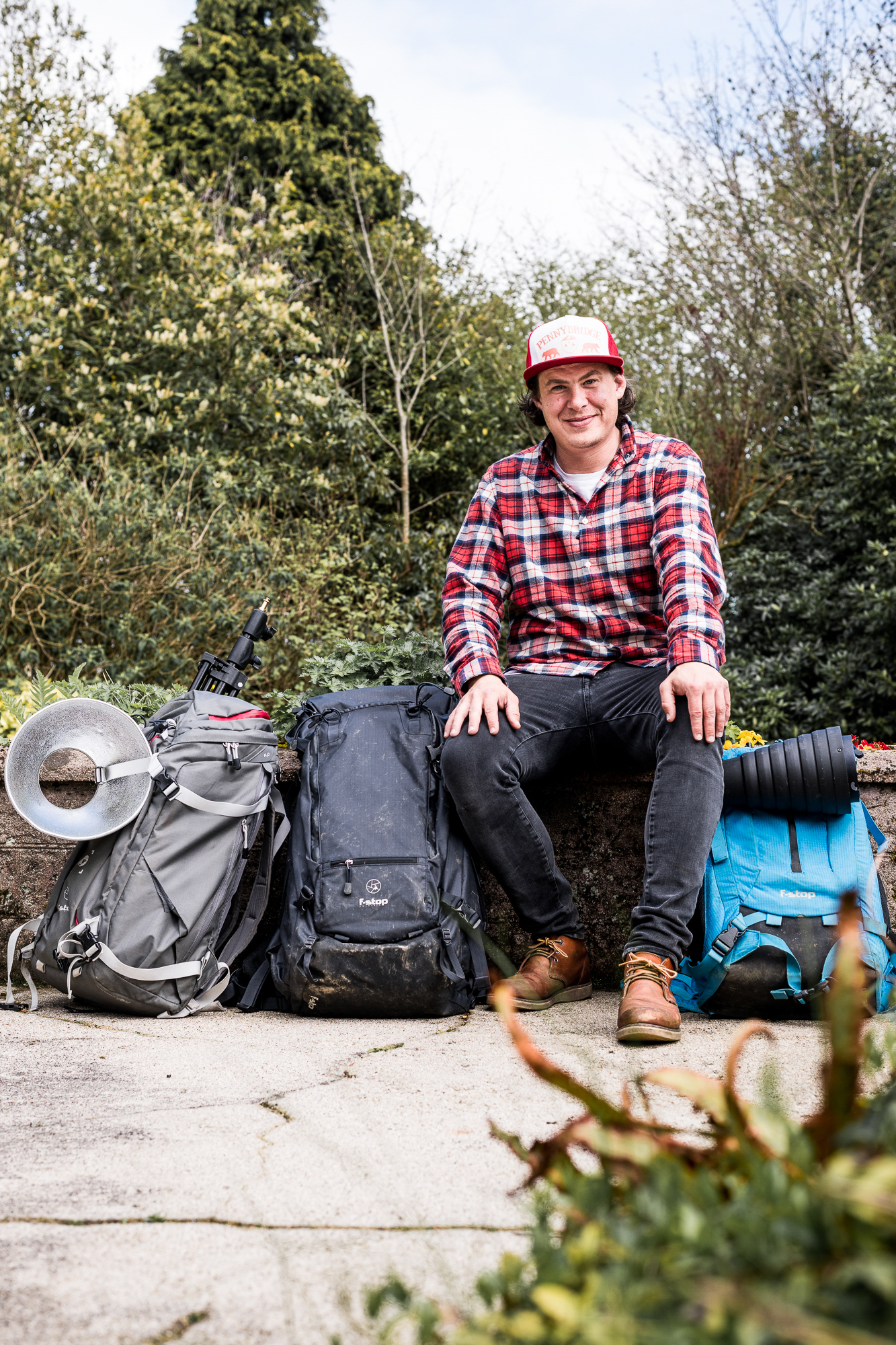 Lorenz sitting beside his backpacks outside in the forest