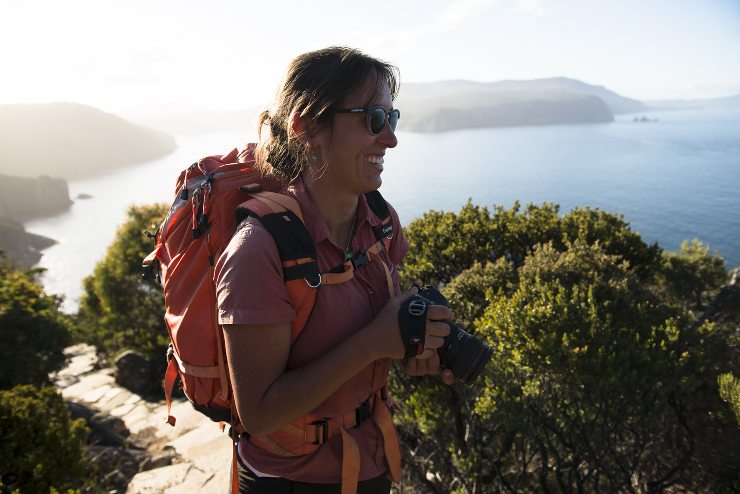 Woman holding camera and wearing f-stop backpack outside