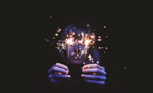 Person on black background holding sparklers
