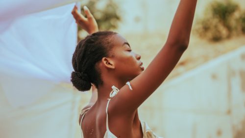 Portrait of a Black women raising her hands to the sky