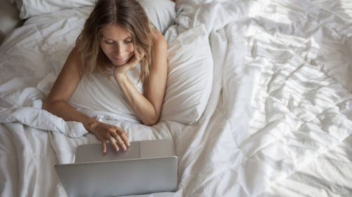 Women laying on her bed working on her laptop