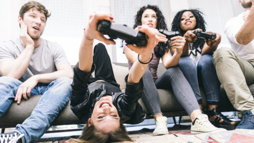Group of friends playing hard with video games. young people sitting in the living room and playing together