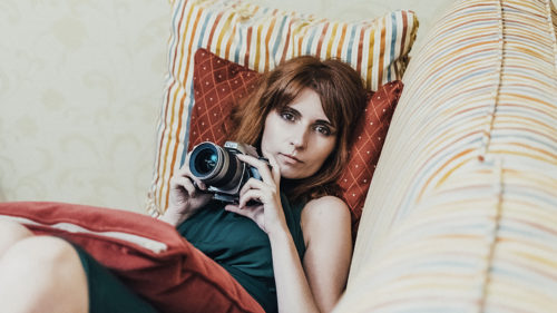 red haired women laying on a couch looking at the camera