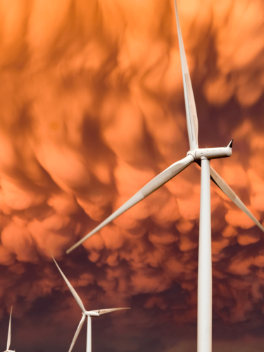 Wind turbines set against a dramatic orange sky, capturing color harmony between natural elements and man-made structures.
