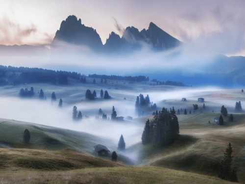 A dreamy mountain landscape with soft fog and mist drifting across rolling hills at dawn, perfect for fog and mist photography.