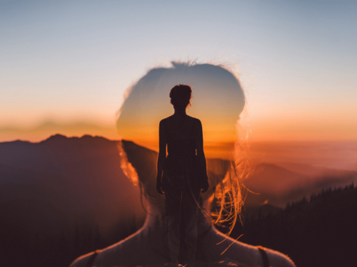 A silhouette of a woman blended with a mountain sunset scene, showcasing the creative blending of elements through multiple exposures.