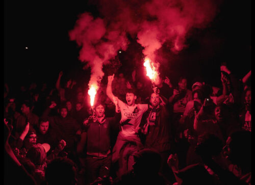 Winning photo from the 2025 OnePlus Photography Awards showing fans celebrating at night with red flares during Midnight Celebration.