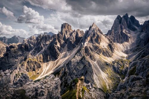 Landscape photo by Graeme Ian Hall capturing dramatic jagged peaks of the Dolomites under moody clouds with light and shadow highlighting mountain ridges.