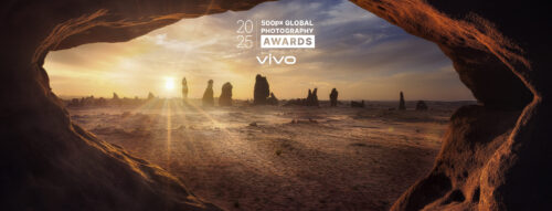 Sunset landscape framed by a rocky cave opening, featured in the 500px Global Photography Awards 2025.