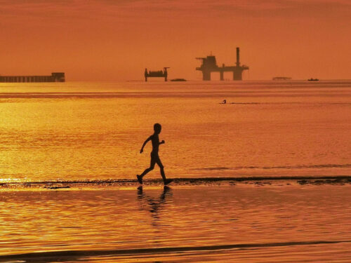 Low-angle view of a modern architectural building against a dramatic sky, emphasizing perspective and composition for photography improvement.