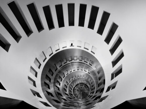 Black and white spiral staircase viewed from above, showcasing framing techniques through circular repetition and geometric symmetry.
