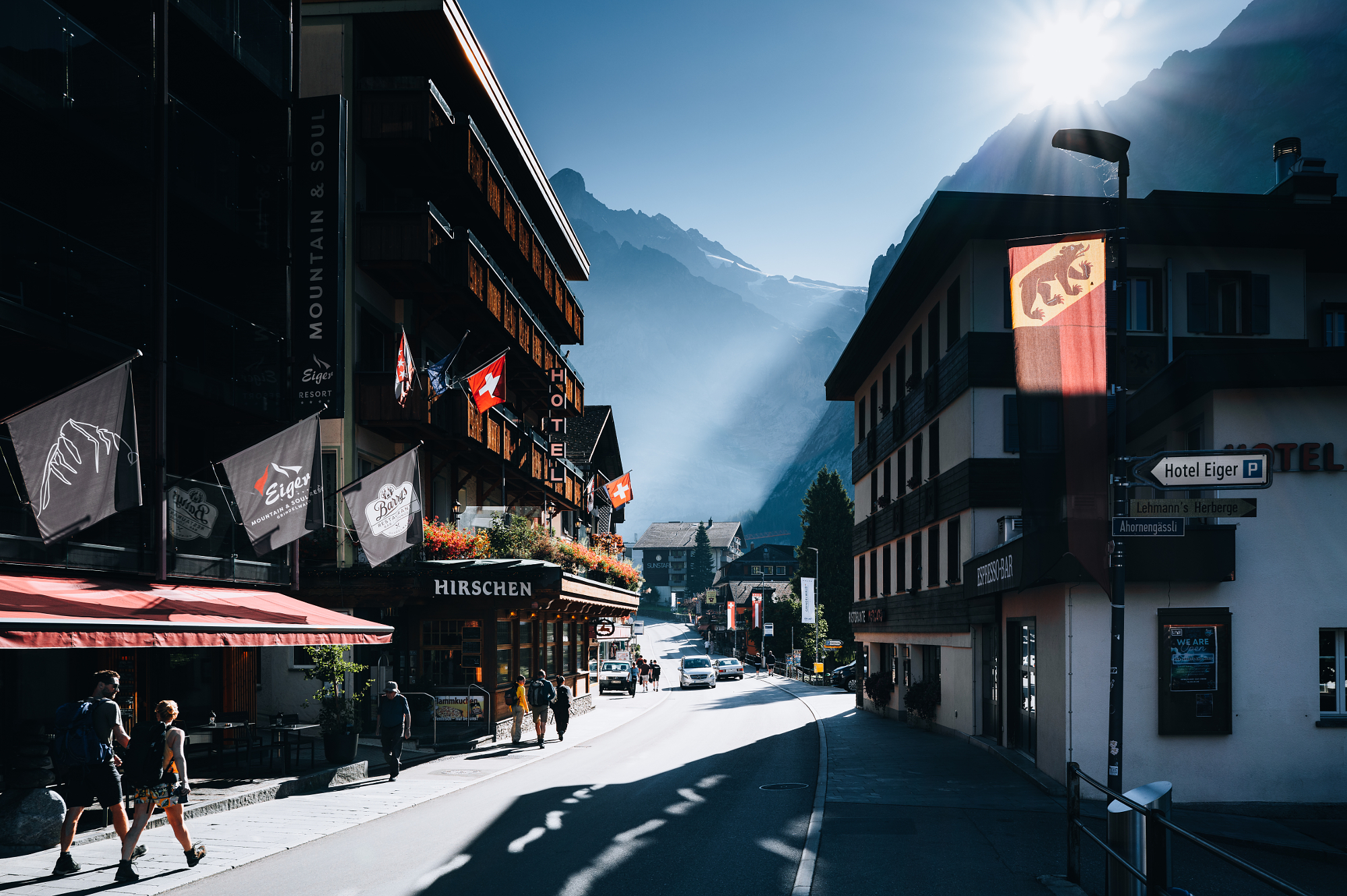 Sunlit alpine village street with mountains in the background, travel photography by Leon Eule.