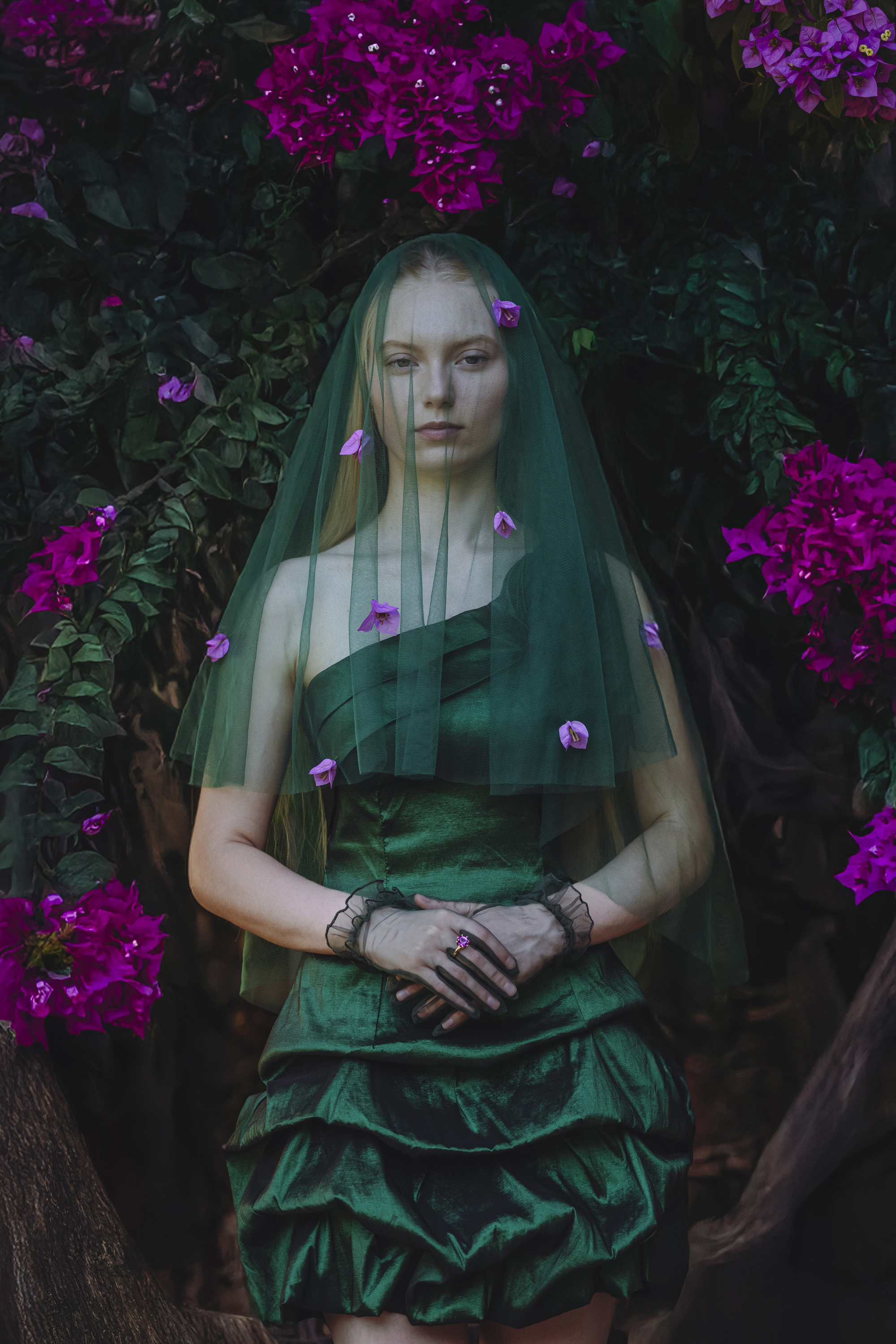 Olena Leliuk creative portrait of a woman in a green dress surrounded by vibrant flowers, showcasing cinematic style and artistic composition