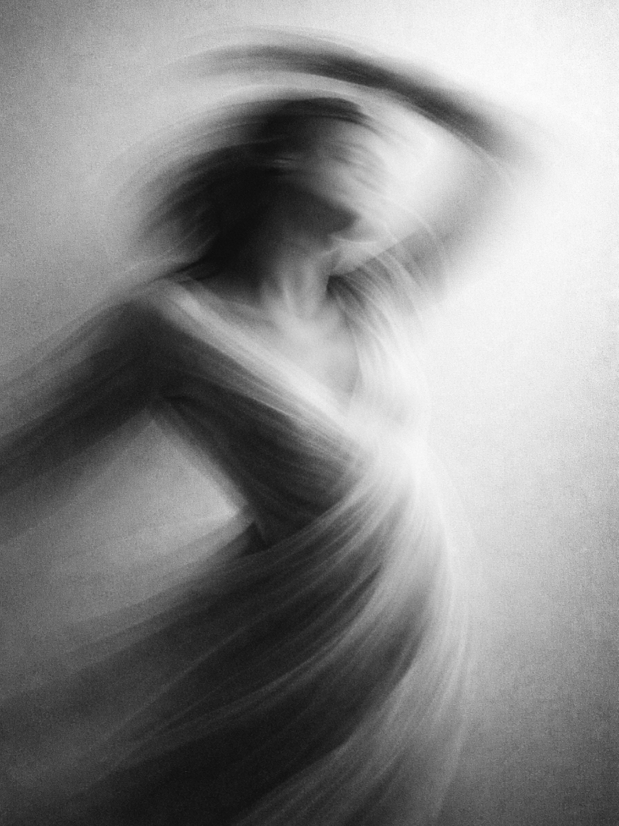 Motion blur photography of an abstract human figure in black and white, creating soft flowing movement and ethereal form