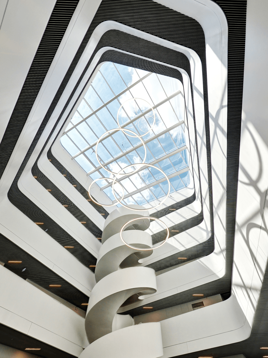 Natural light composition of a modern architectural interior with spiral staircase and skylight creating geometric patterns