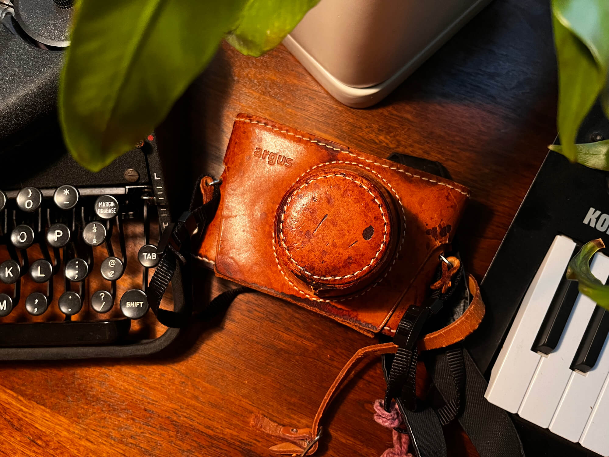 Vintage Argus film camera on a wooden desk with warm lighting, reflecting the analog photography style of Mikey Rogers.