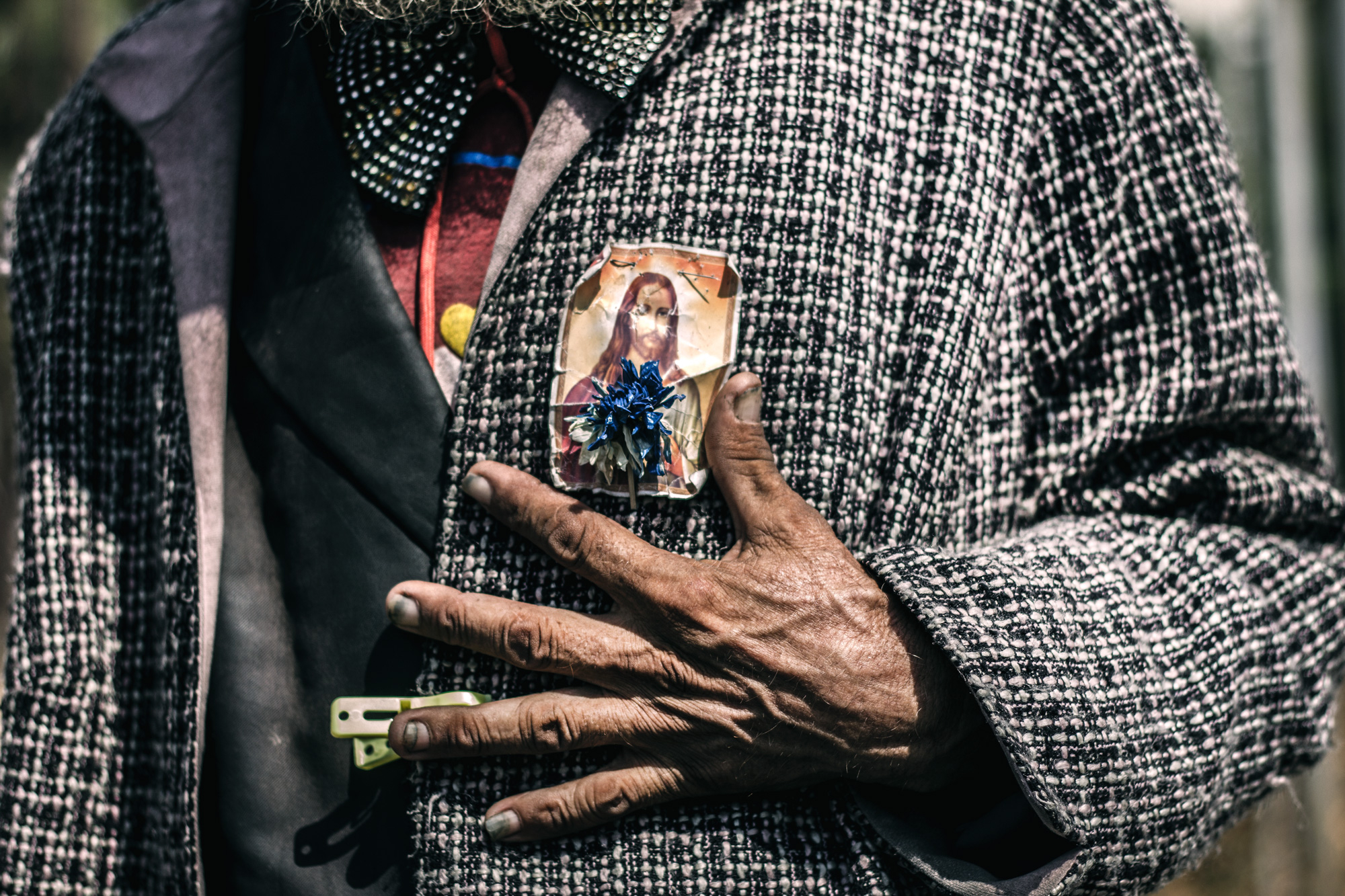 Hand resting on a jacket with a religious pin.