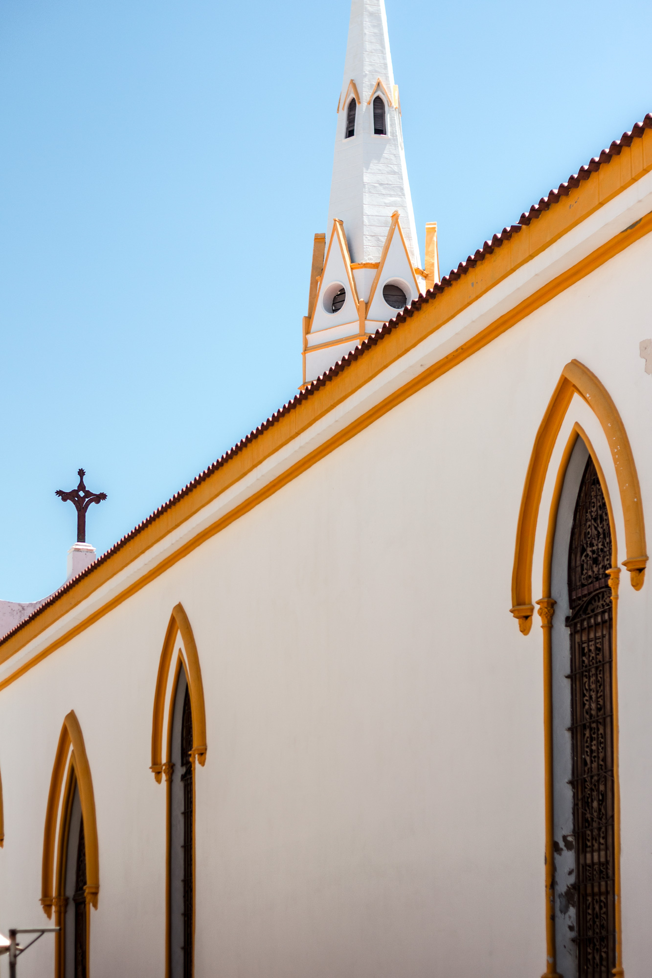 White church exterior with yellow trim and steeple.