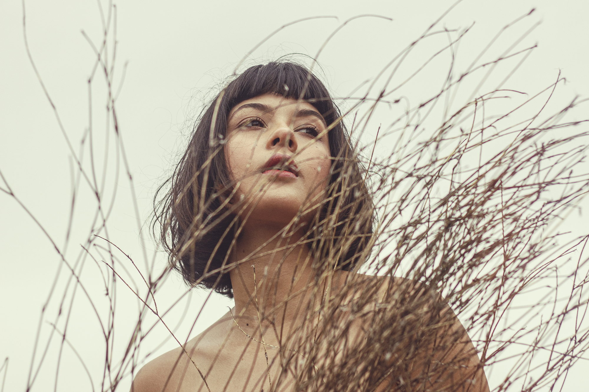 Woman standing in tall, dry grass.