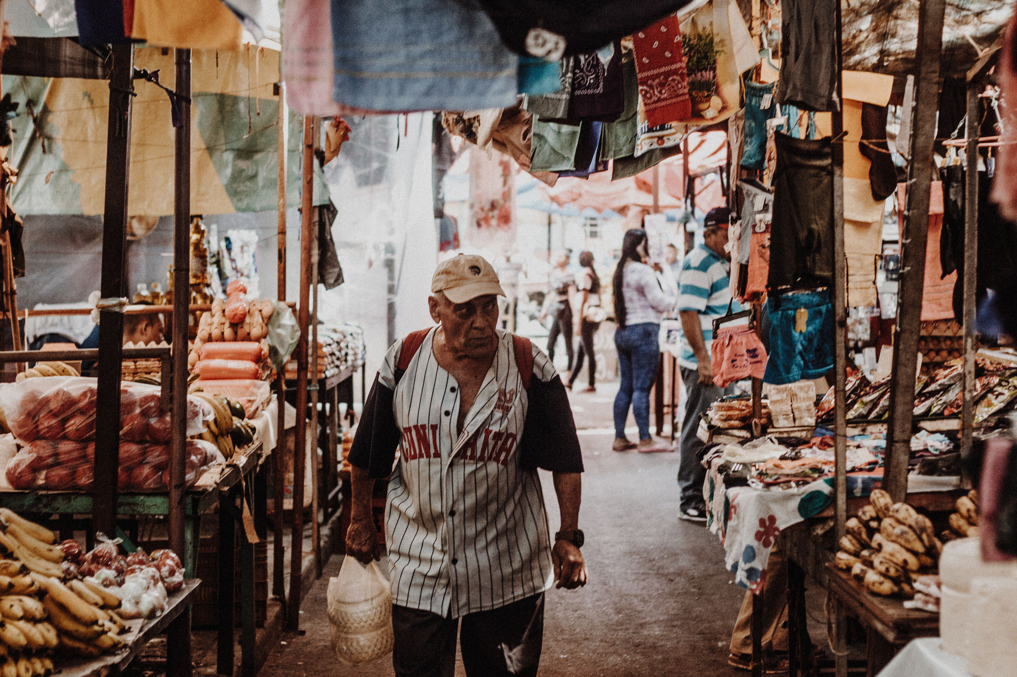 Older man walking through a busy outdoor market.