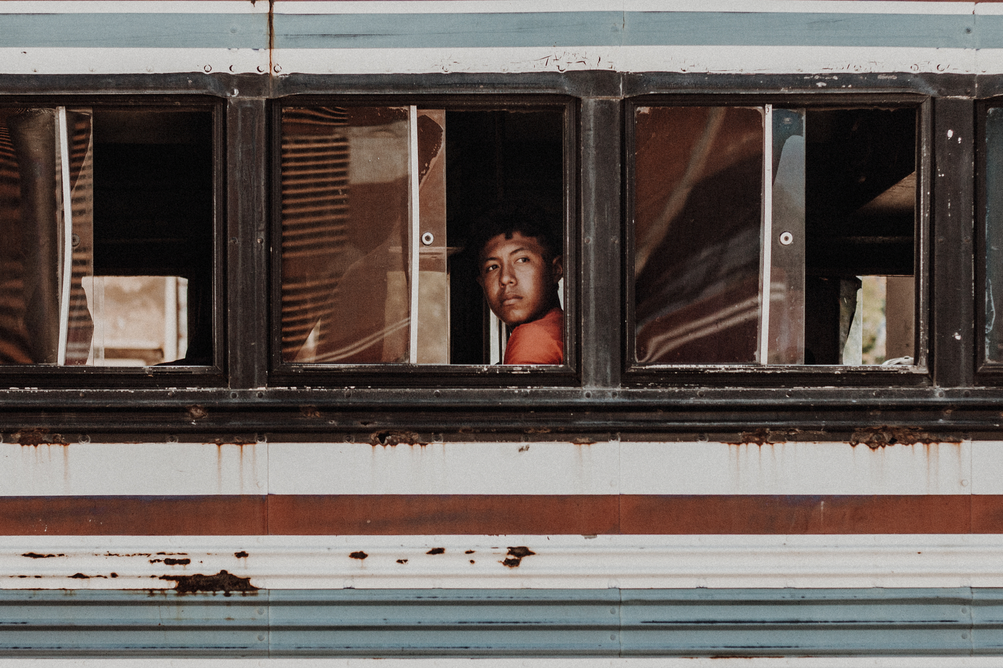 Young boy looking out of a weathered window.