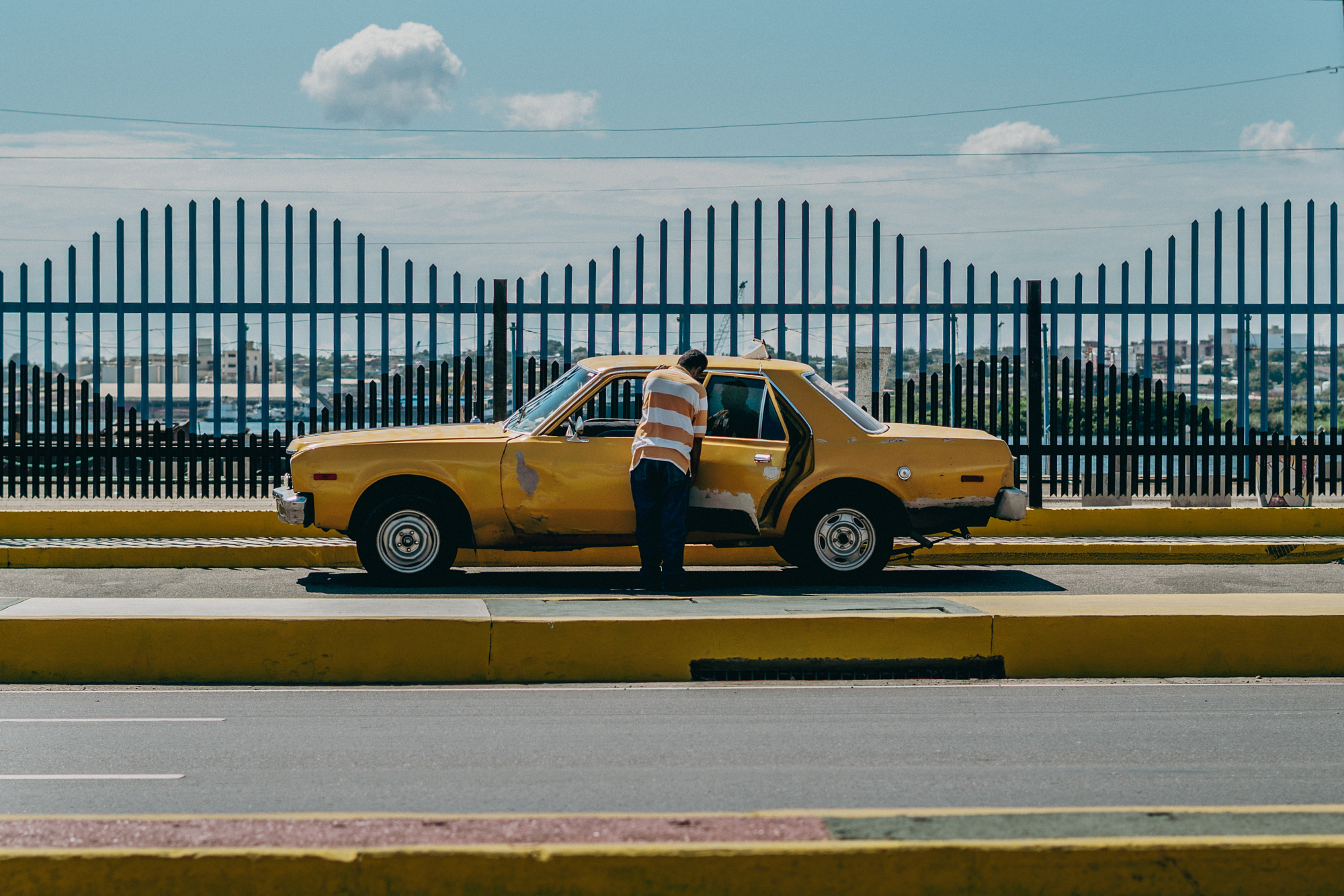 Man standing by an open door of a yellow taxi.