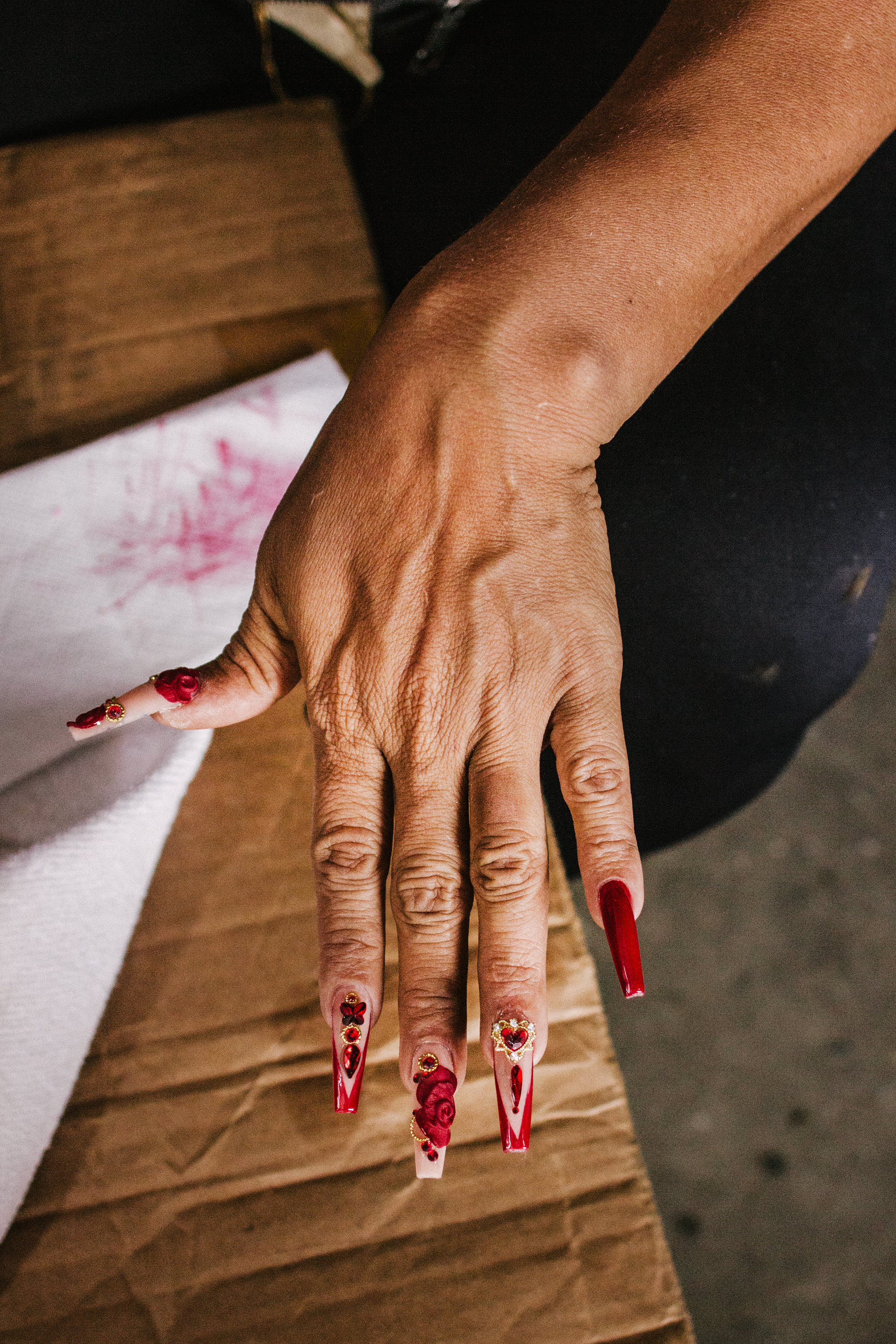 Hand with long, decorative red fingernails.