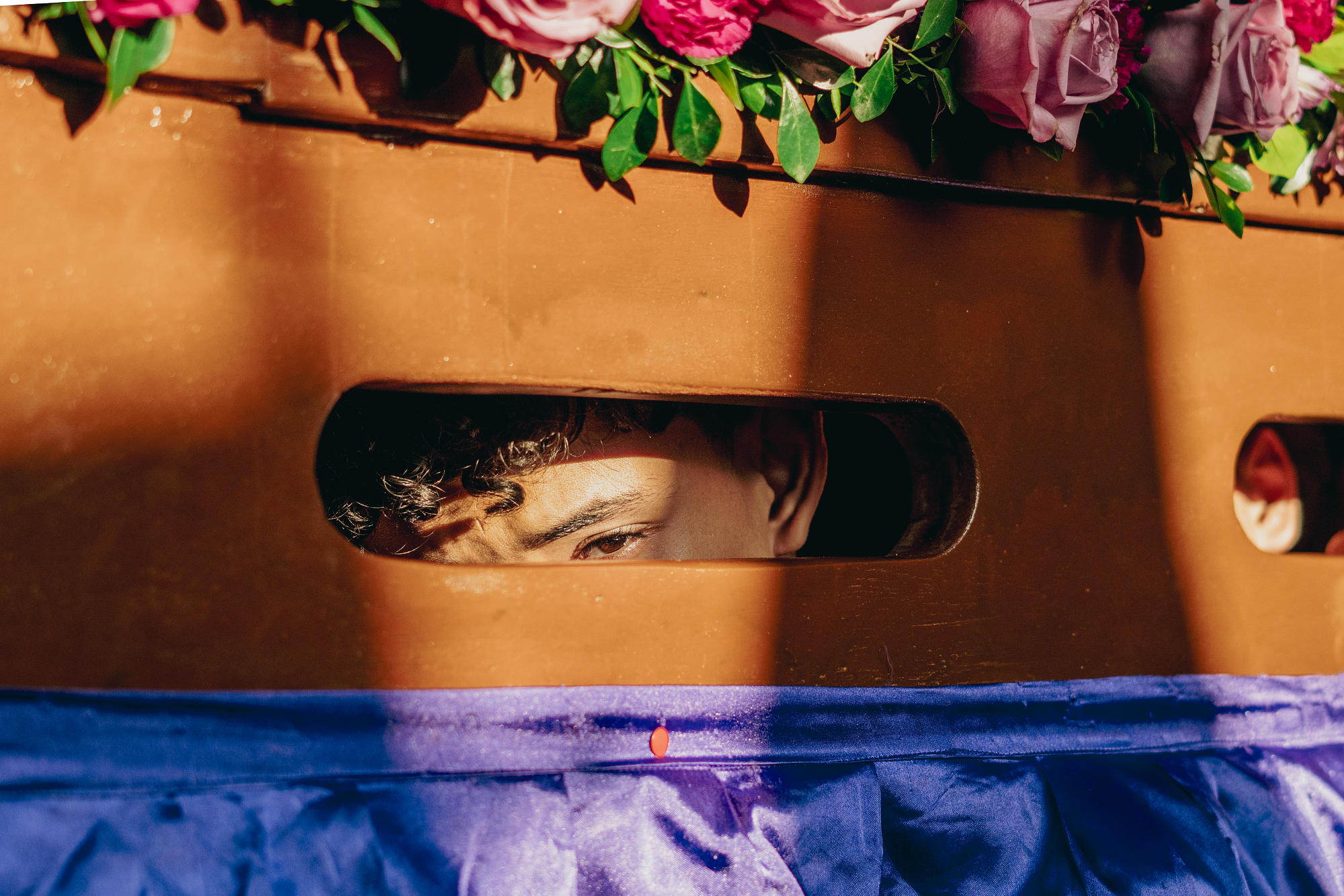 Boy's eyes looking through a slot in a wood frame.