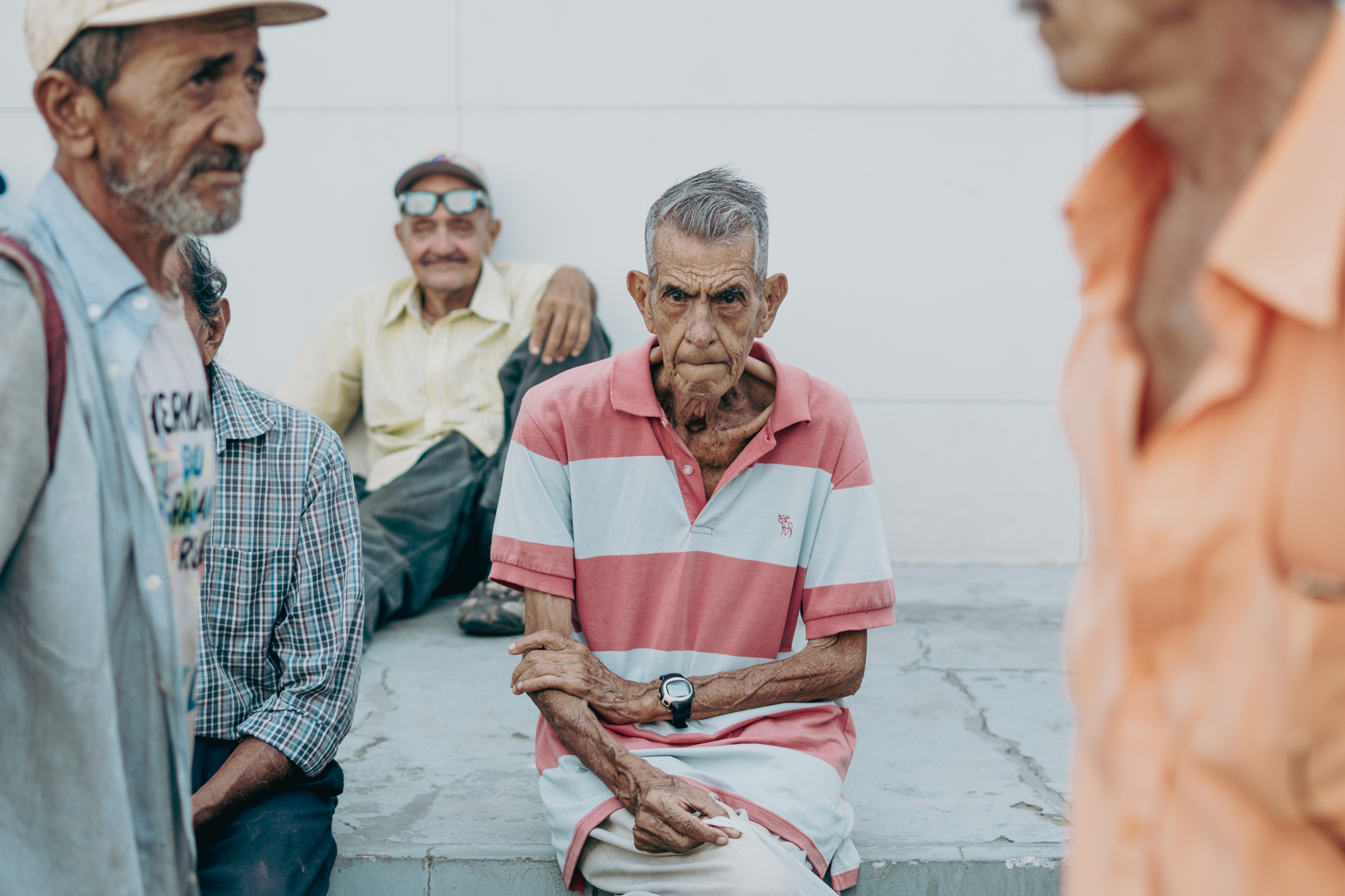 Three older men sitting together on a city stoop.