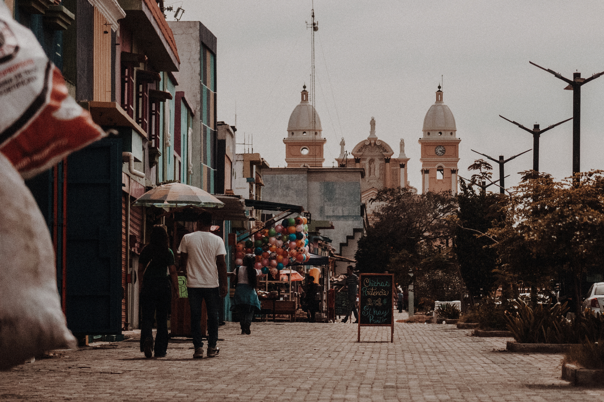 People walking down a street toward a domed church in city.