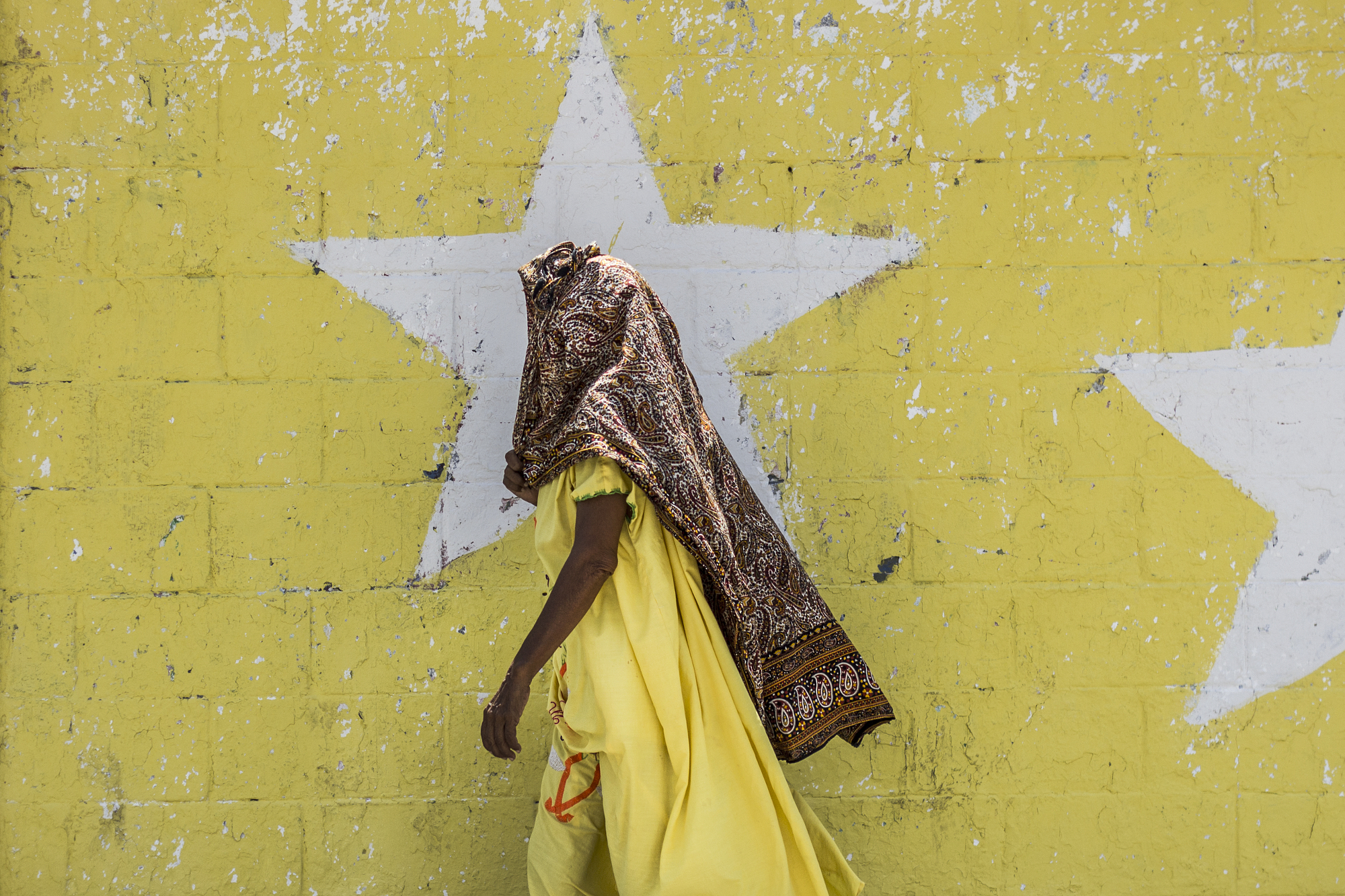 Person in yellow walking past a yellow star wall.