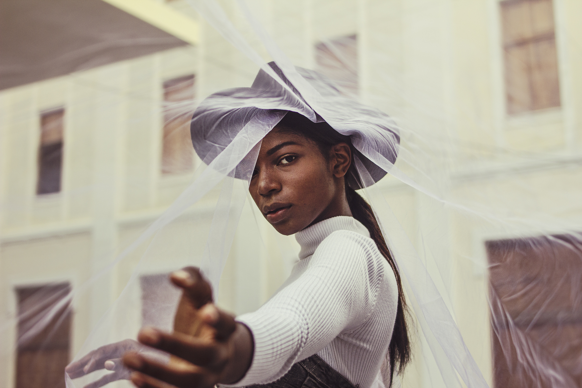 Woman in white with sculptural headpiece reaching out.