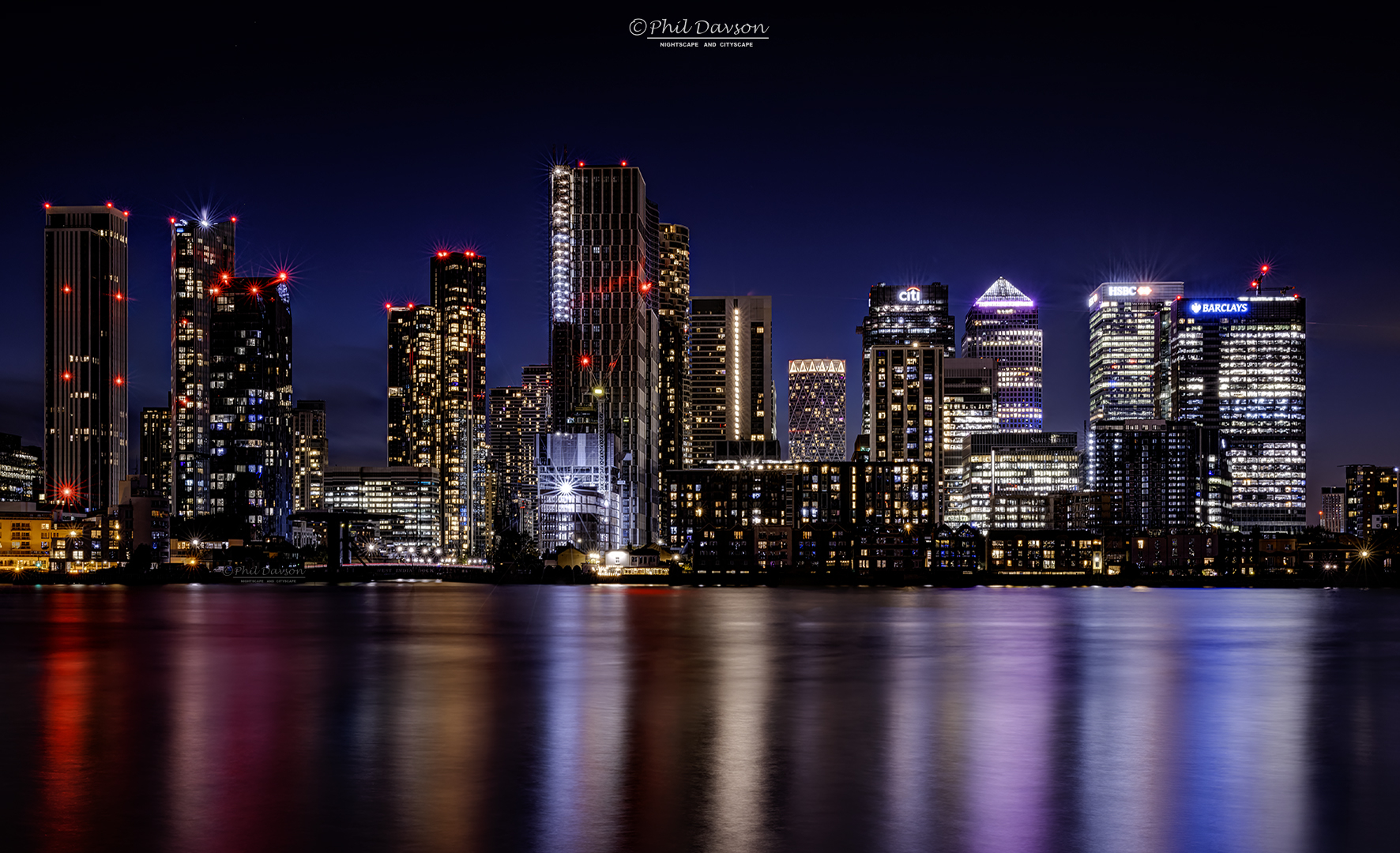 Urban nightscape photography by Phil Dawson photographer showcasing the Canary Wharf skyline lit up during blue hour.