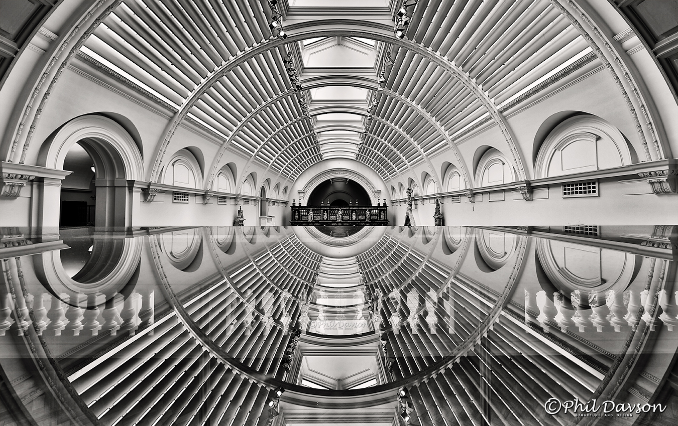 Wide-angle architectural view looking straight down a massive symmetrical metal tunnel structure.