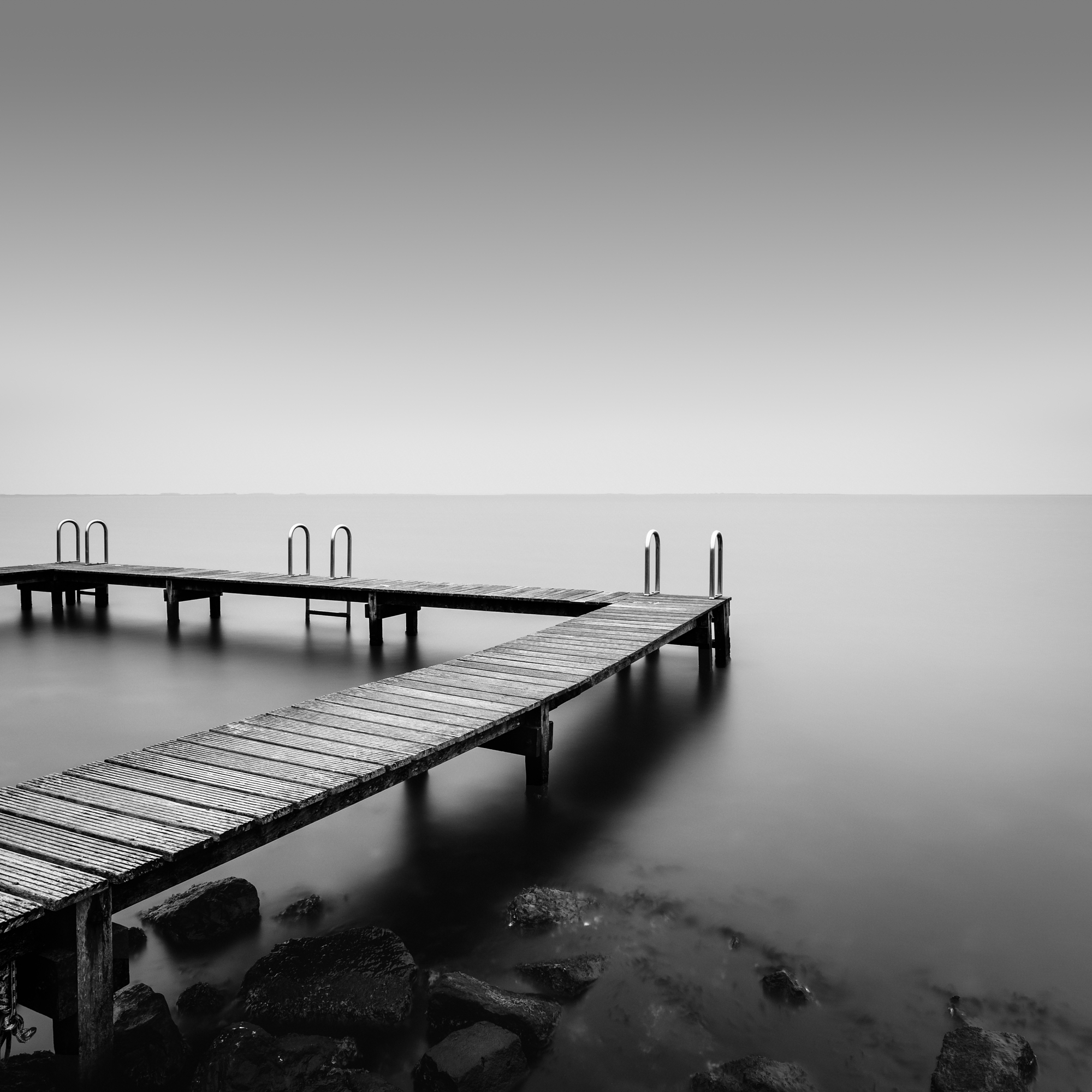 Minimalist long exposure photography of a quiet wooden ocean pier.