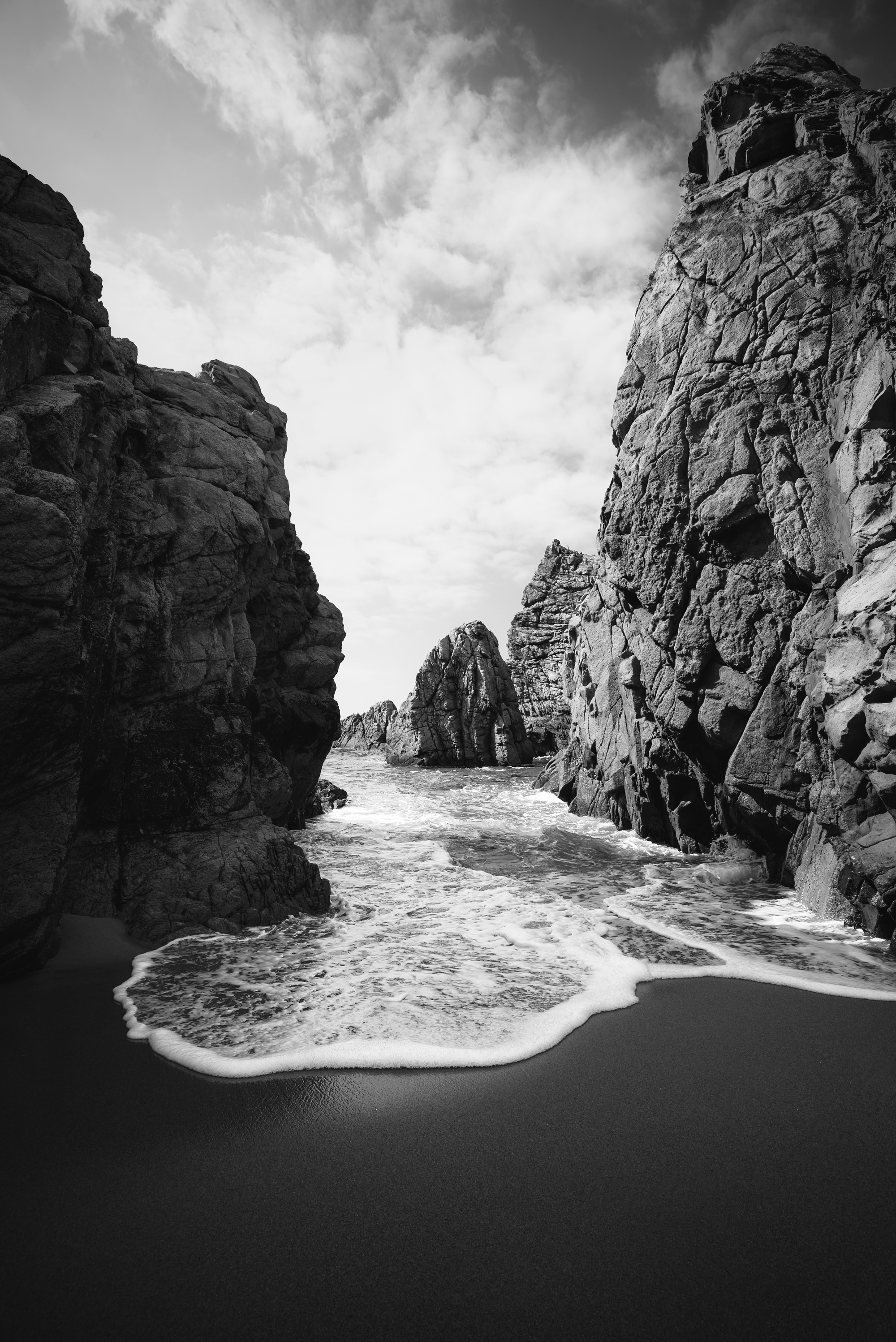 Black and white landscape photography of a dramatic rocky ocean cove.