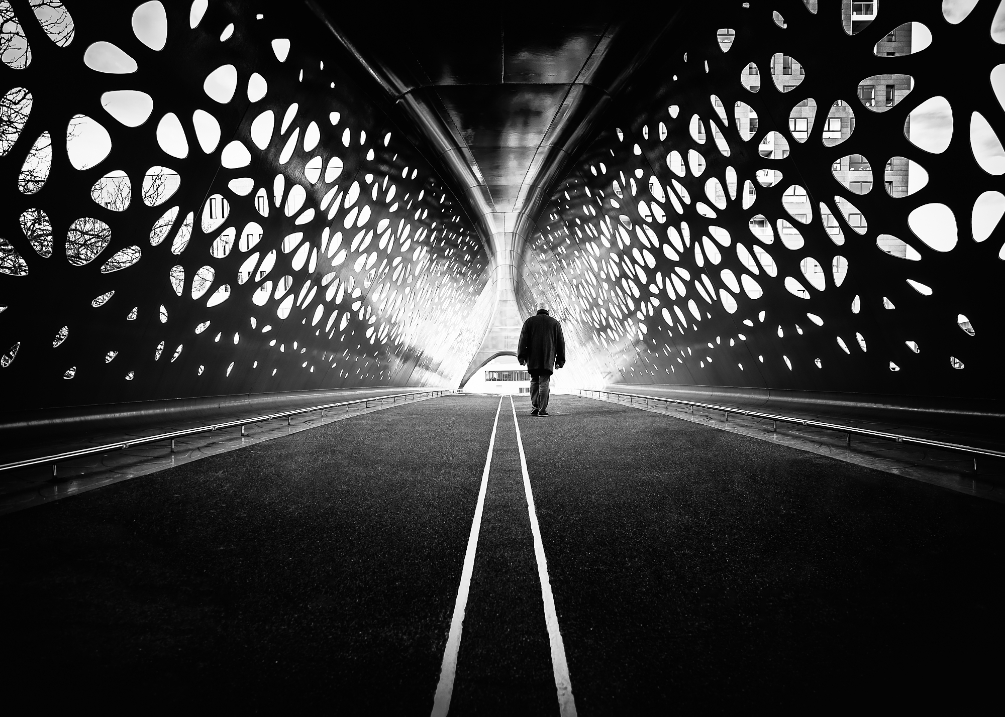 Minimalist photography techniques showing a person in a patterned tunnel.