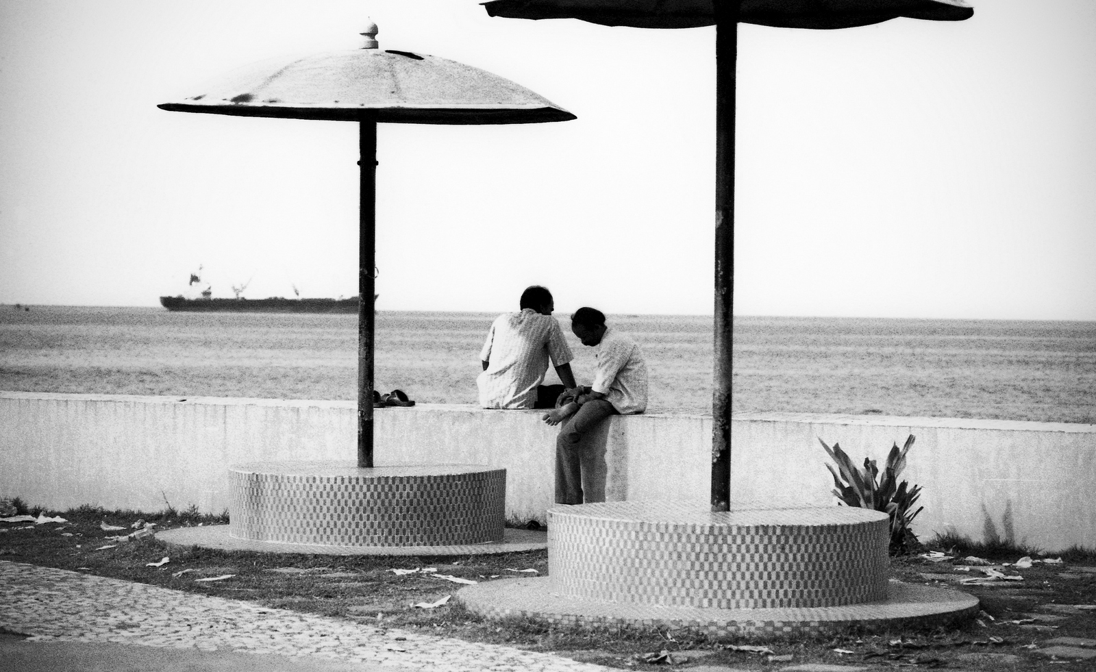 Contemplative individual looking at the ocean, illustrating timeless black and white street photography.