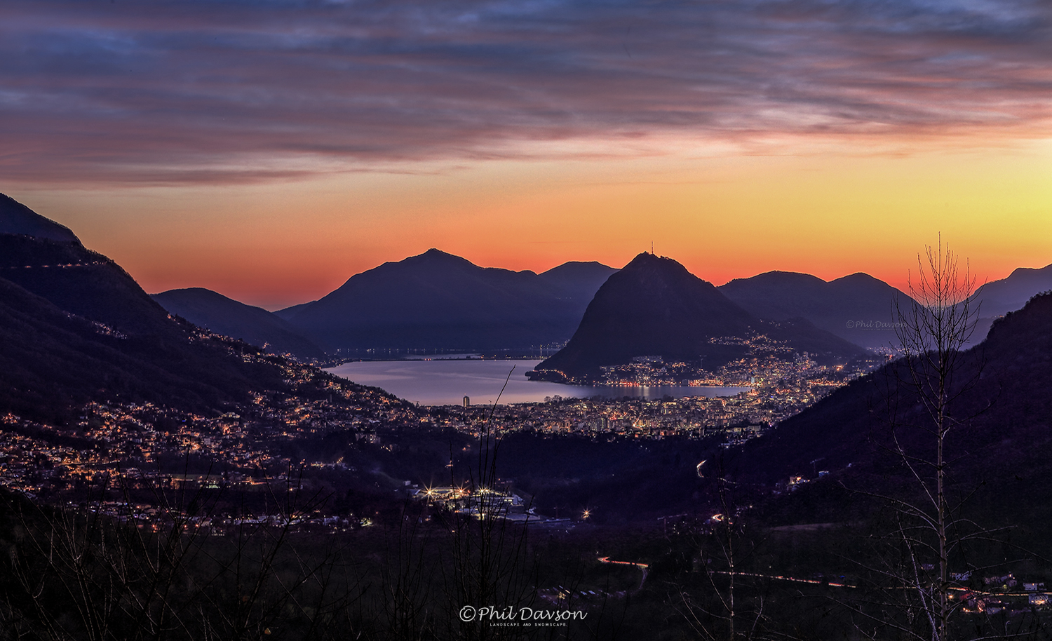 Beautiful scenic view of Lake Lugano at sunset with dramatic mountains.