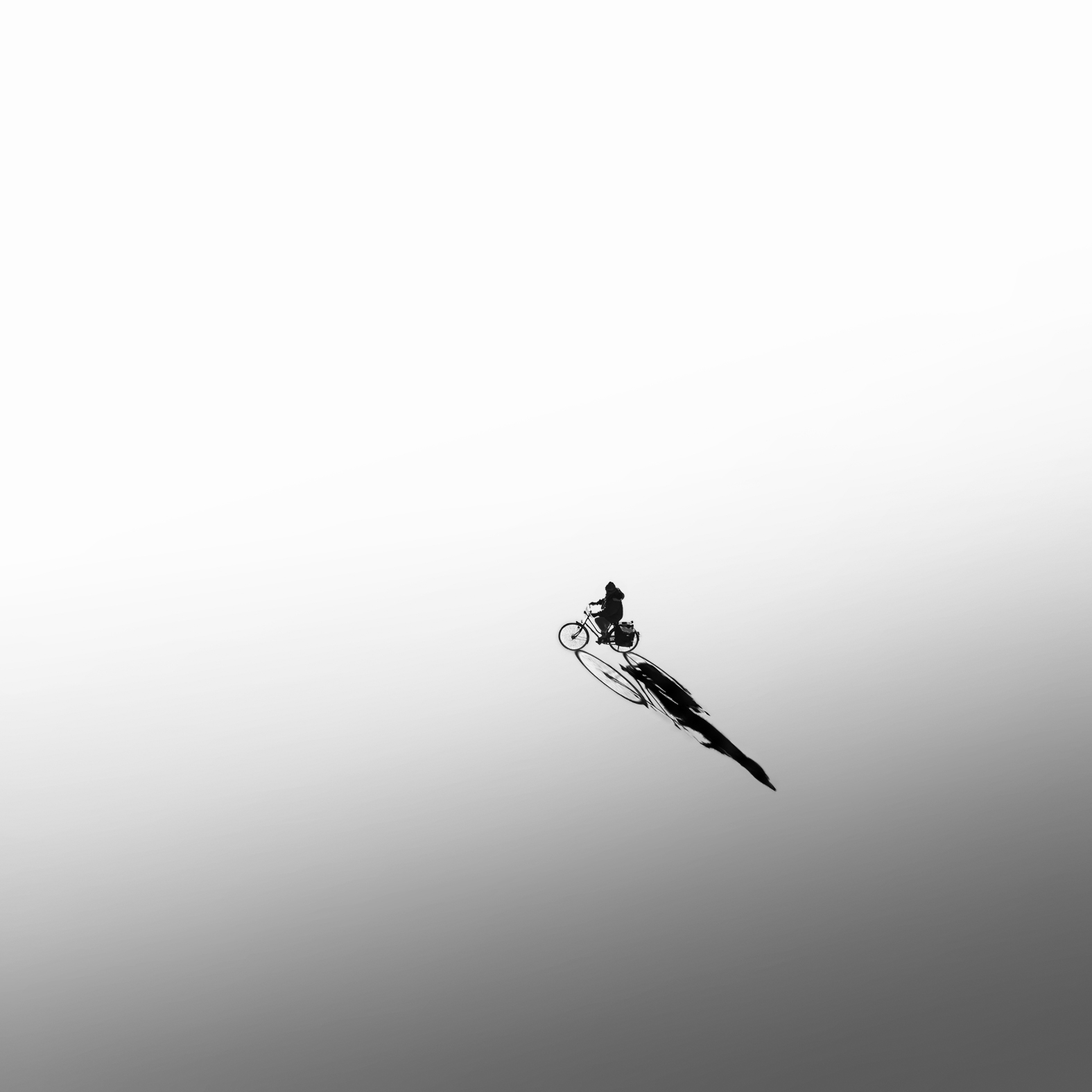 Minimalist photography techniques showing a cyclist's shadow.