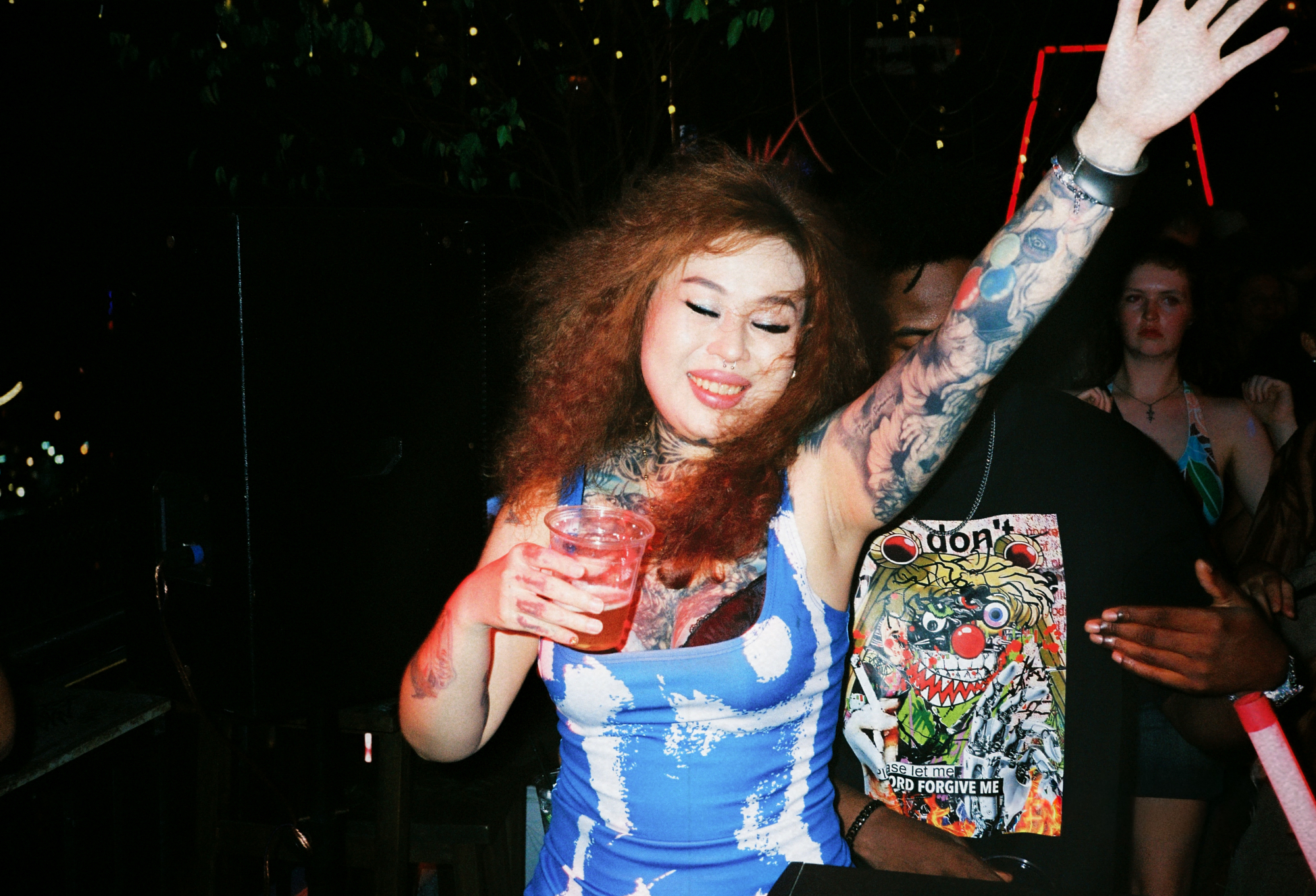 A joyful woman dancing with a drink at a music event, showcasing authentic human connection and Southeast Asia street photography vibes.
