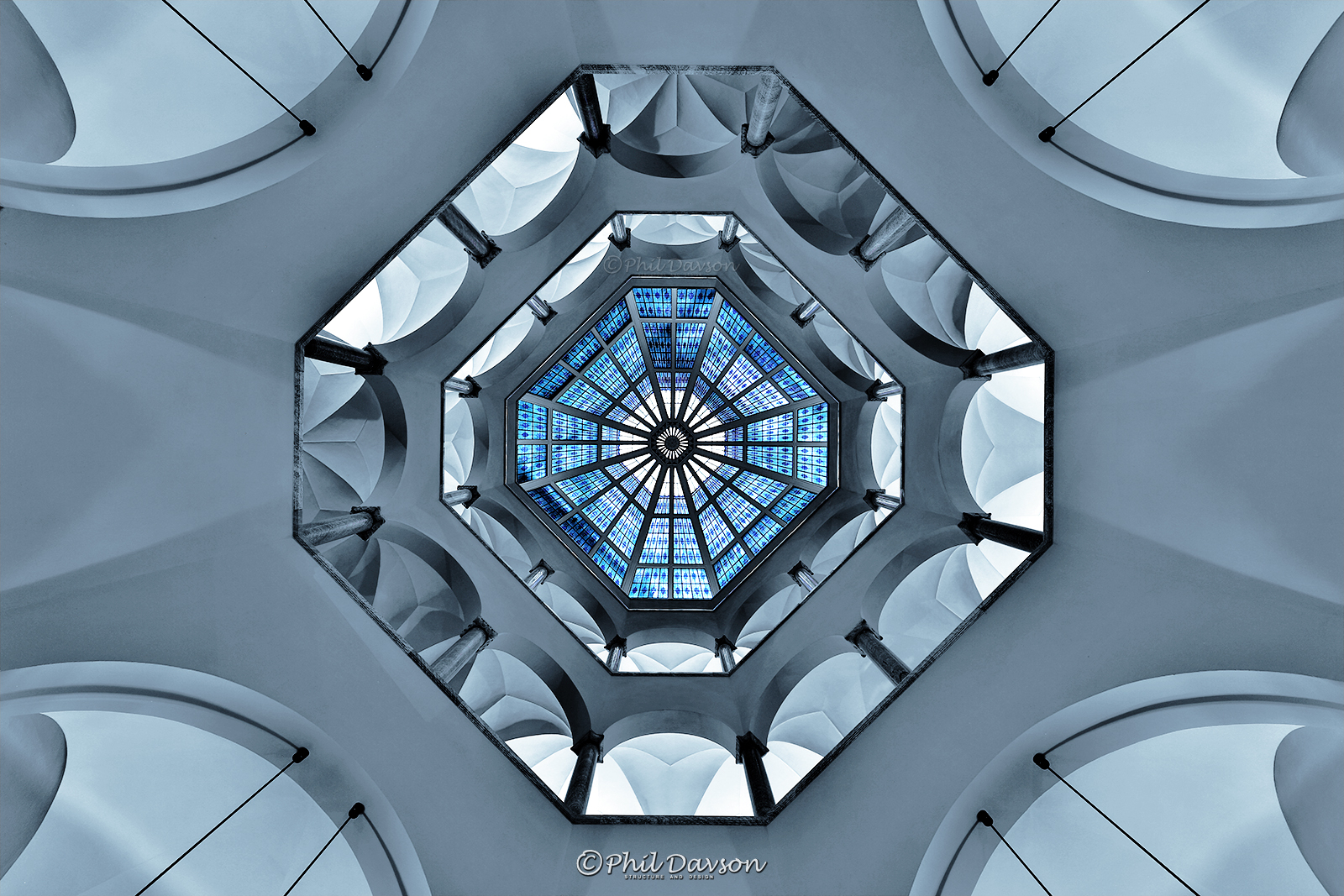 Symmetrical architectural perspective looking up at a modern skylight window structure.