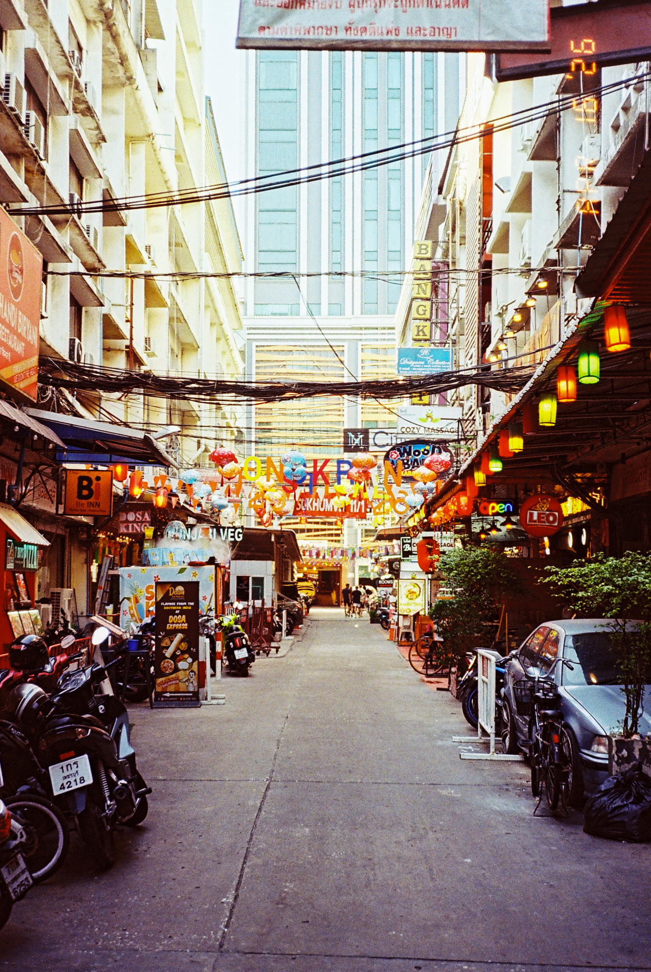 Southeast Asia street photography capturing a narrow, vibrant alleyway in Thailand adorned with hanging colorful lanterns.