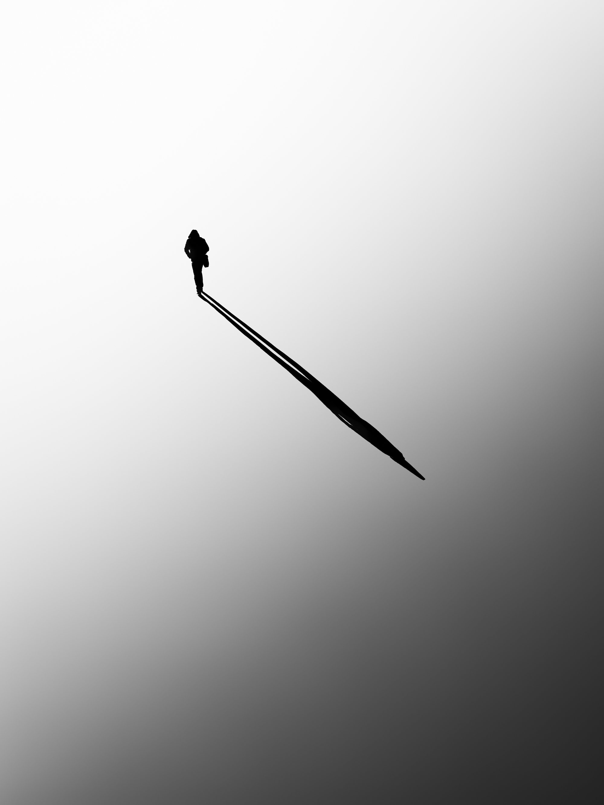 Minimalist photography techniques with a lone silhouette and long shadow.